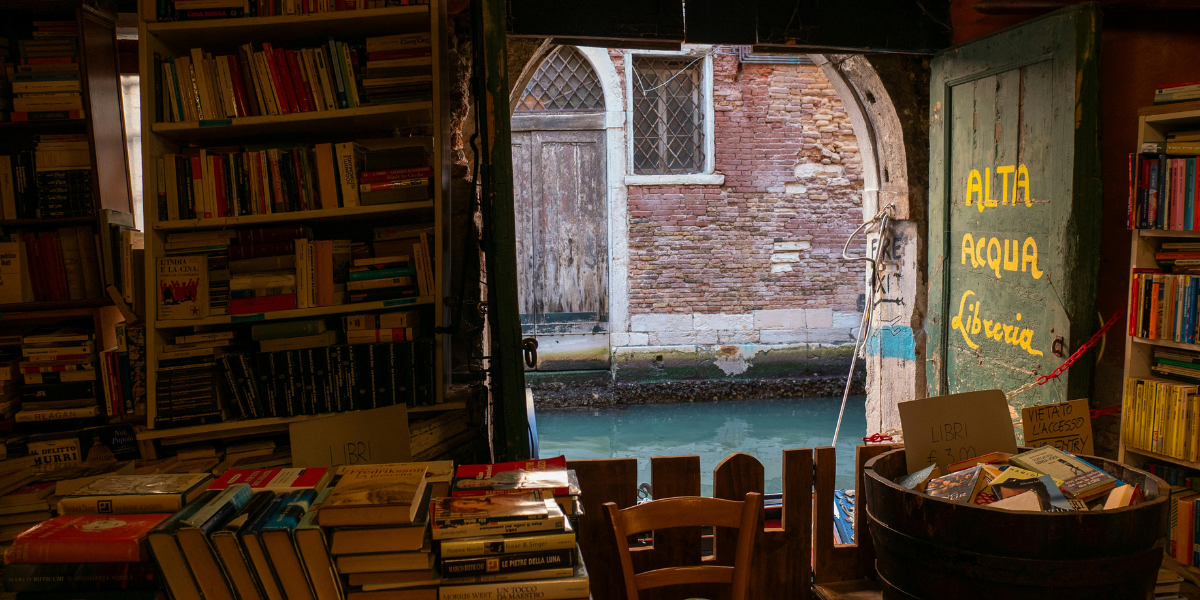 A stack of non-fiction books on a desk next to a notebook and pen, ready for a student to read over the summer